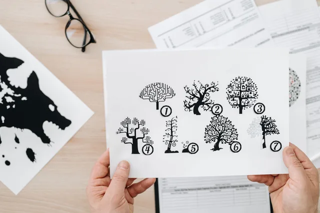 Close-up showing hands holding paper with tree test illustration for psychological assessment. The honest guide to MBTI analysts traits