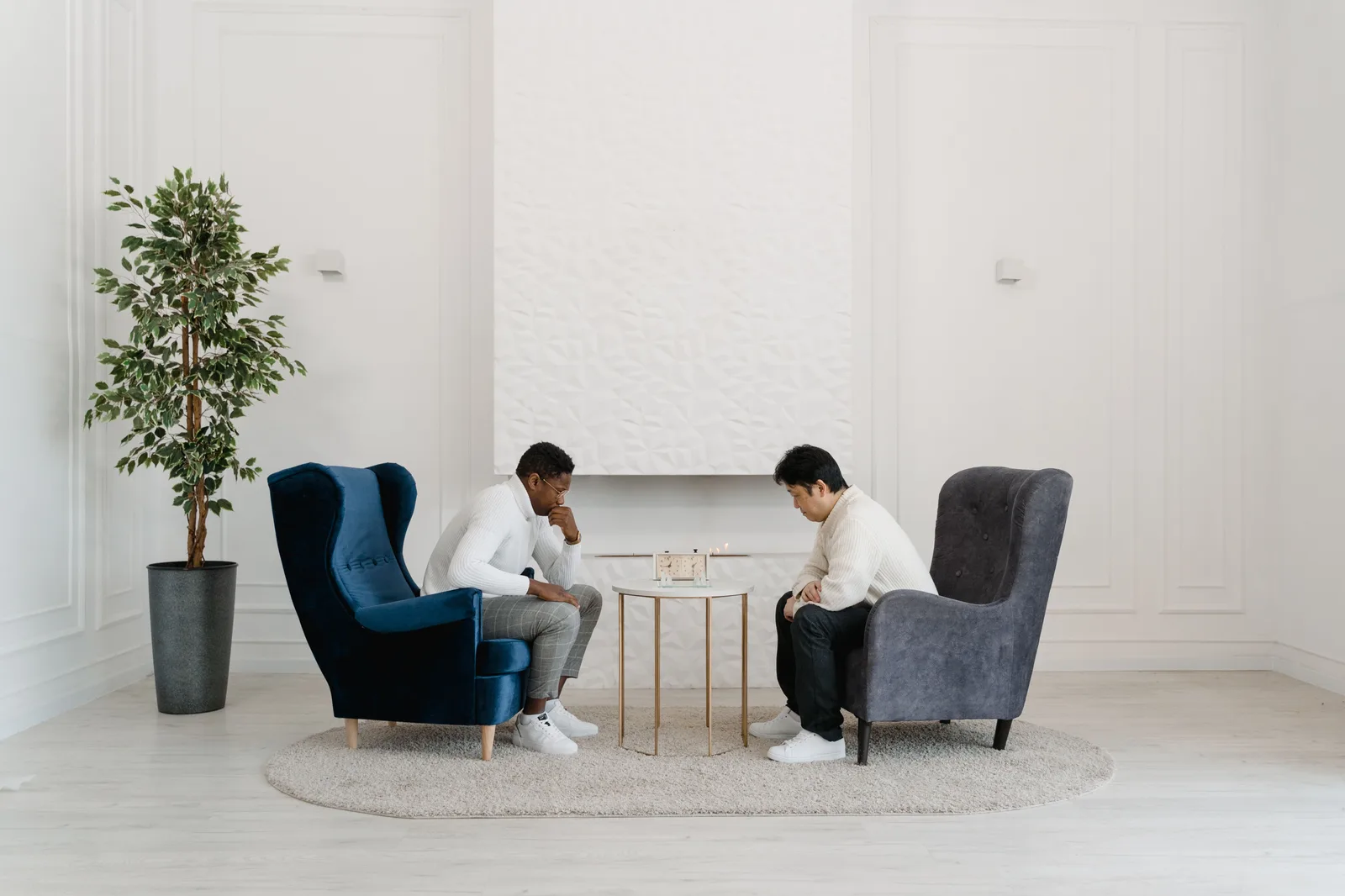 Two men seated in armchairs focus on a strategy board game in a modern, minimalist room. 5 points worth checking on MBTI sentinels compatibility