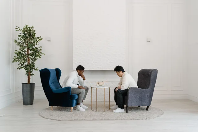 Two men seated in armchairs focus on a strategy board game in a modern, minimalist room. 5 points worth checking on MBTI sentinels compatibility